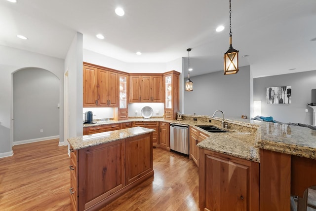 kitchen with sink, light wood-type flooring, stainless steel dishwasher, kitchen peninsula, and pendant lighting