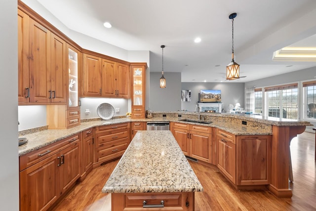 kitchen with a kitchen island, sink, a kitchen bar, hanging light fixtures, and kitchen peninsula