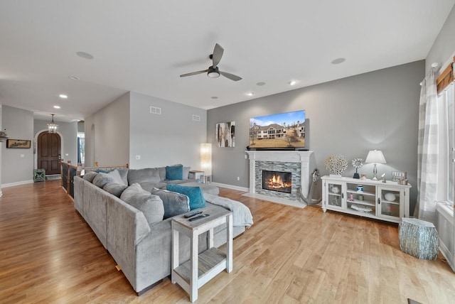 living room featuring ceiling fan, a fireplace, and light hardwood / wood-style floors