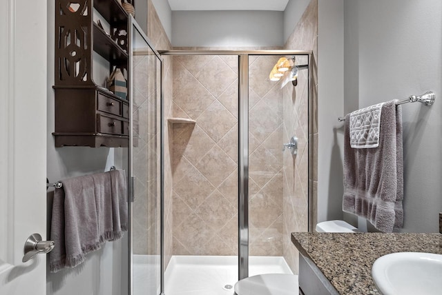 bathroom featuring vanity, a shower with door, and toilet