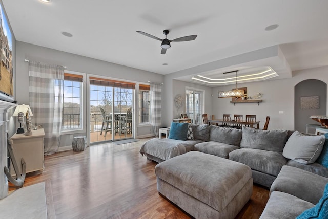 living room featuring ceiling fan, a tray ceiling, and hardwood / wood-style floors