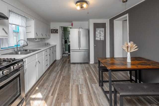 kitchen with white cabinetry, sink, light wood-type flooring, and appliances with stainless steel finishes