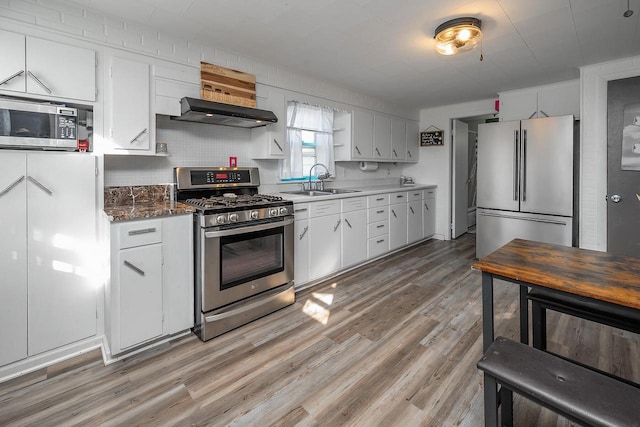 kitchen featuring white cabinetry, sink, stainless steel appliances, and dark stone countertops