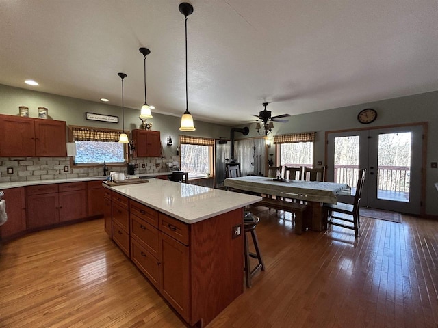 kitchen featuring hanging light fixtures, decorative backsplash, wood finished floors, and a center island