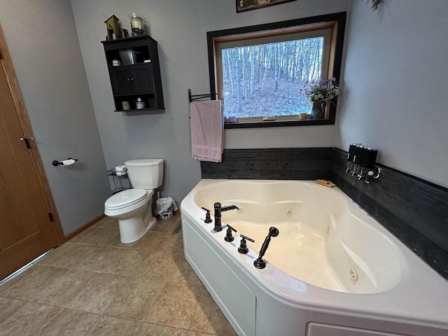 bathroom featuring toilet, baseboards, and a whirlpool tub