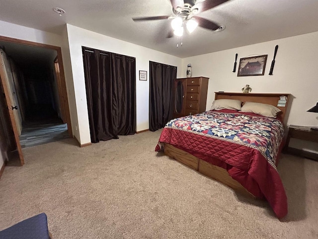 bedroom with a ceiling fan, light carpet, a textured ceiling, and two closets