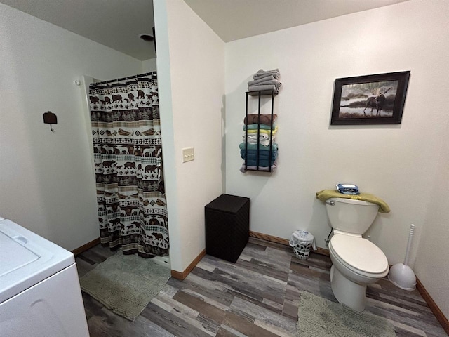 full bathroom featuring toilet, washer / dryer, baseboards, and wood finished floors