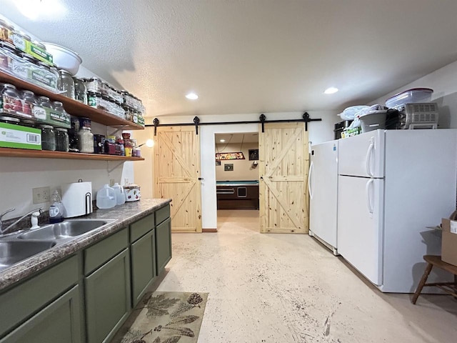 kitchen with a barn door, recessed lighting, a sink, freestanding refrigerator, and dark countertops