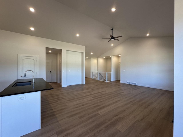 unfurnished living room with dark wood-type flooring, ceiling fan, lofted ceiling, and sink