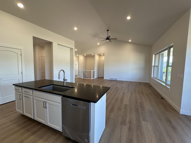 kitchen featuring lofted ceiling, sink, white cabinetry, stainless steel dishwasher, and a kitchen island with sink