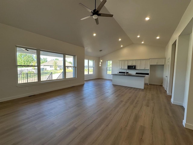 unfurnished living room with wood-type flooring, ceiling fan, and high vaulted ceiling