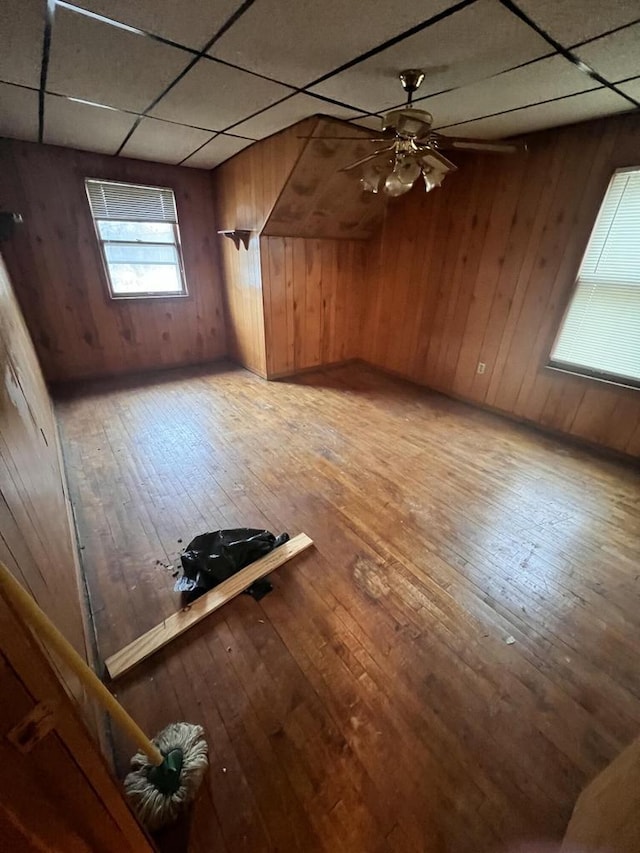 additional living space featuring ceiling fan, hardwood / wood-style floors, and wooden walls