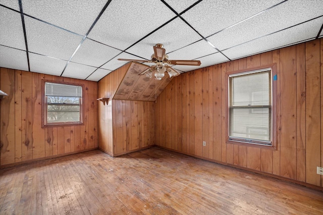 bonus room featuring wooden walls, ceiling fan, and light wood-type flooring