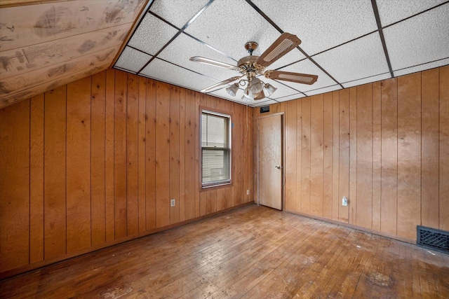 interior space featuring wood-type flooring, ceiling fan, and wood walls