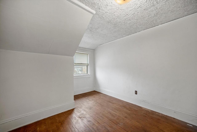 bonus room with lofted ceiling, hardwood / wood-style flooring, and a textured ceiling