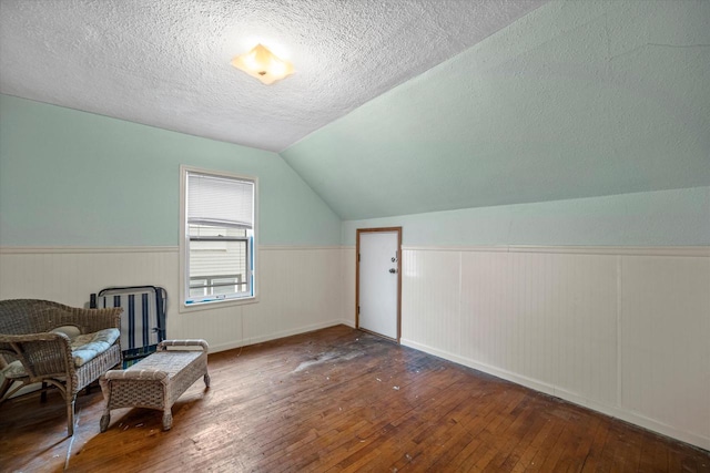 sitting room with wood-type flooring, lofted ceiling, and a textured ceiling