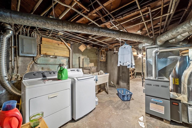 basement featuring washer and dryer, sink, electric panel, and heating unit