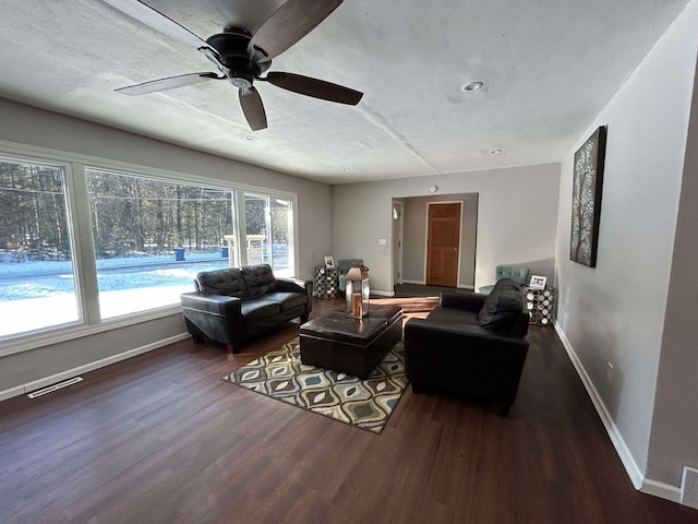 living room with ceiling fan, dark wood-type flooring, and a textured ceiling