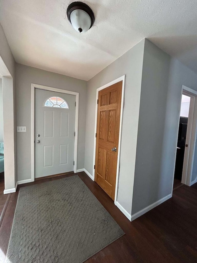 foyer entrance with dark wood-type flooring and a textured ceiling