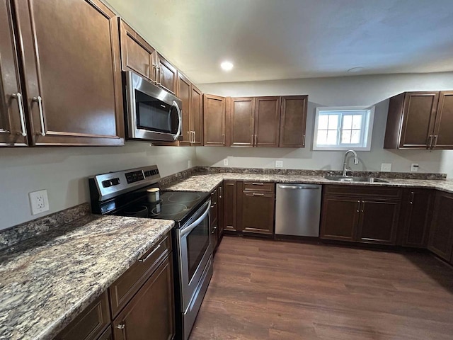 kitchen featuring dark wood-type flooring, stainless steel appliances, sink, and light stone counters