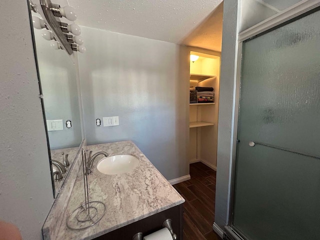 bathroom featuring vanity, an enclosed shower, and a textured ceiling