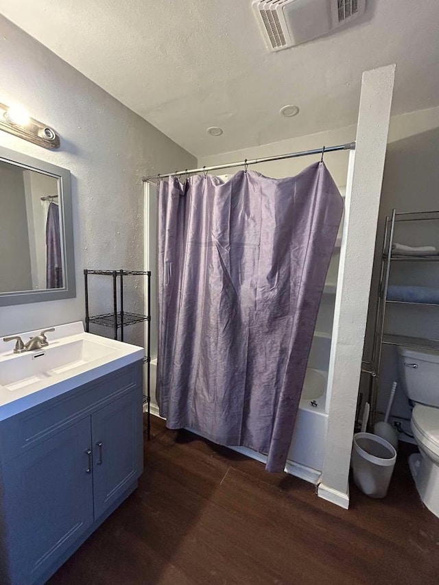 full bathroom featuring toilet, wood-type flooring, a textured ceiling, vanity, and shower / bath combination with curtain