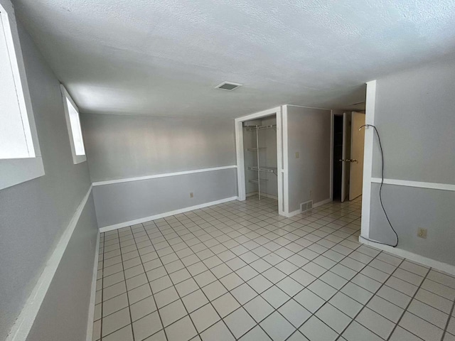 unfurnished room with light tile patterned floors and a textured ceiling