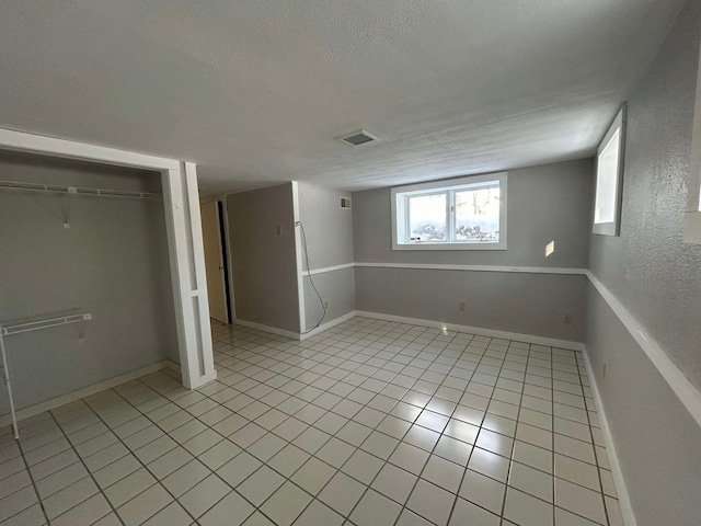 basement featuring a textured ceiling and light tile patterned floors