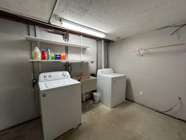 clothes washing area featuring sink, washing machine and dryer, and a textured ceiling