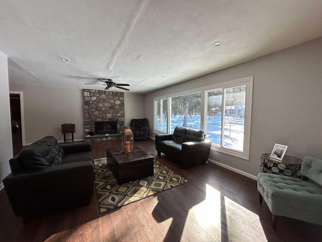 living room with ceiling fan, a fireplace, dark hardwood / wood-style floors, and a textured ceiling