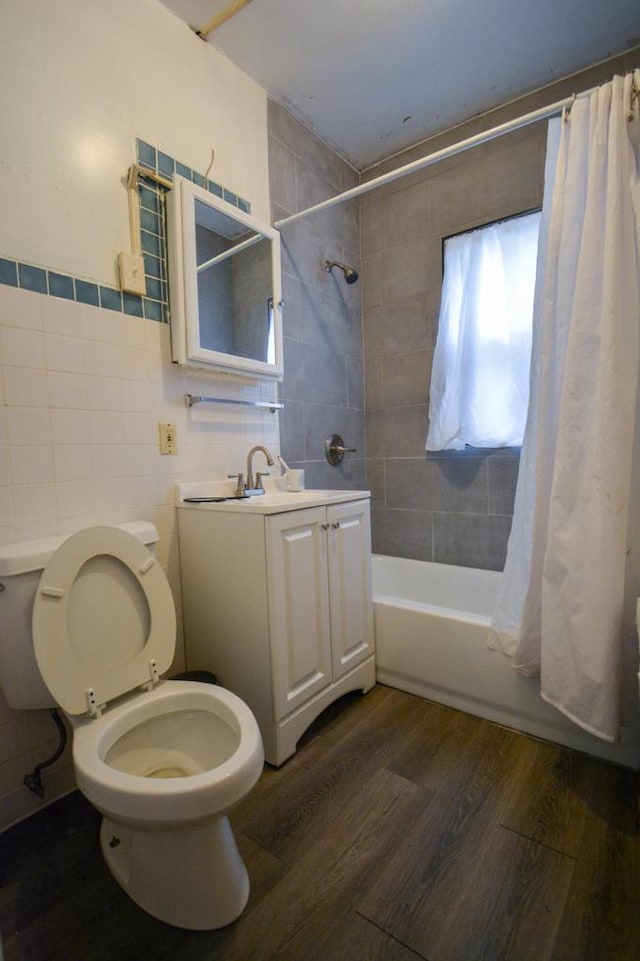 full bathroom with toilet, wood-type flooring, tile walls, vanity, and shower / bath combo