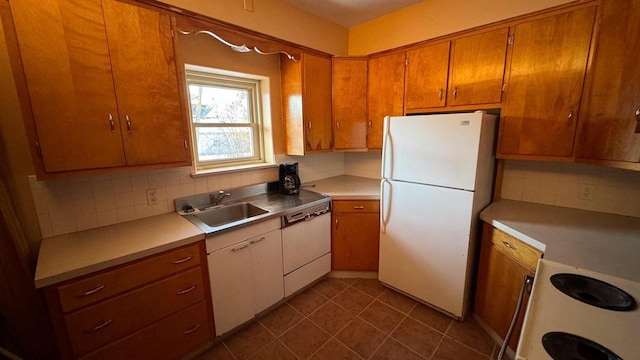 kitchen with white appliances, dark tile patterned floors, sink, and backsplash