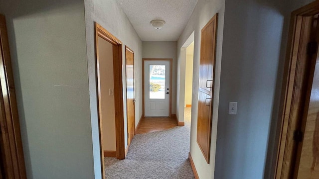 hall with light carpet and a textured ceiling