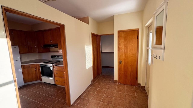 kitchen featuring dark tile patterned floors, backsplash, and white appliances