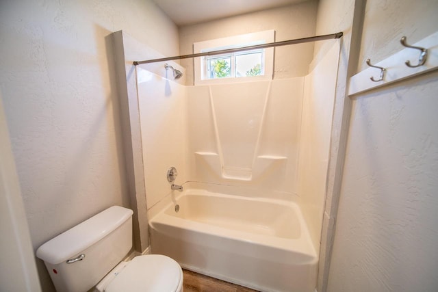 full bathroom featuring toilet, shower / washtub combination, and a textured wall