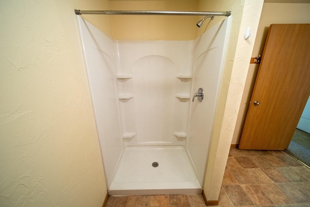 full bath with a shower stall and a textured wall