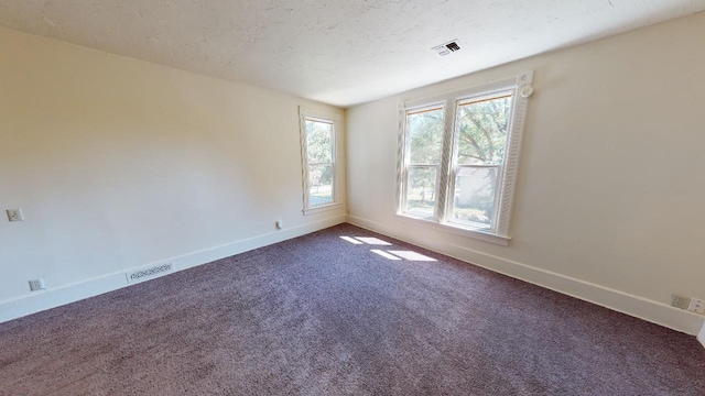 carpeted empty room with baseboards, visible vents, and a textured ceiling