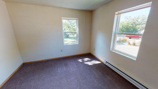 carpeted spare room featuring a baseboard heating unit