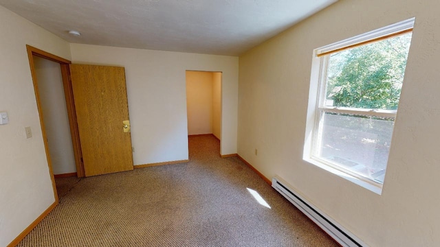 empty room featuring light carpet and a baseboard heating unit