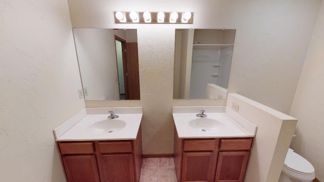 full bathroom with two vanities, a sink, and a textured wall