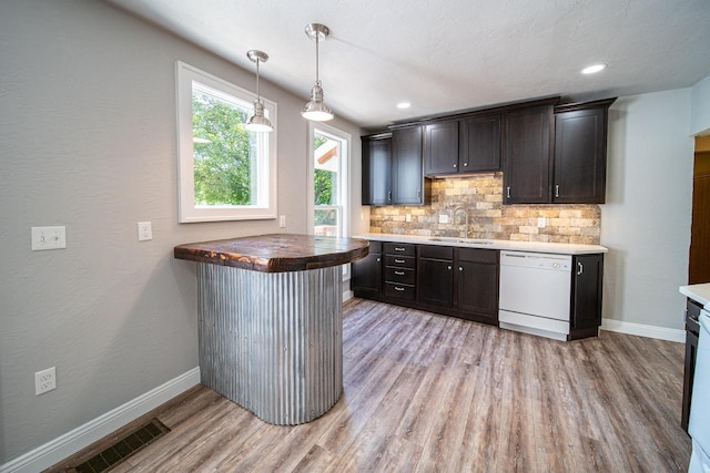 bar featuring tasteful backsplash, visible vents, dishwasher, light wood-style floors, and a sink