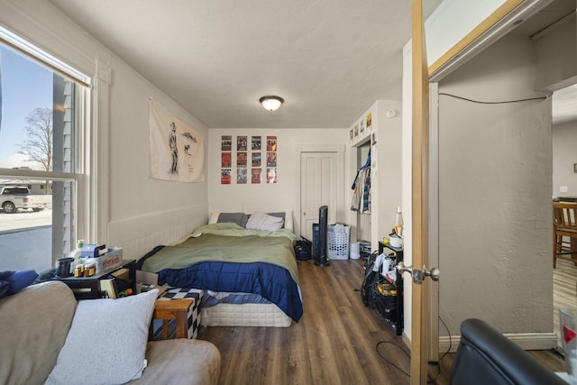 bedroom featuring dark wood-type flooring, a textured wall, and baseboards