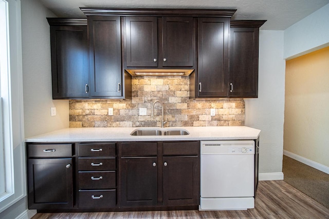 kitchen with dark brown cabinetry, light countertops, white dishwasher, and a sink