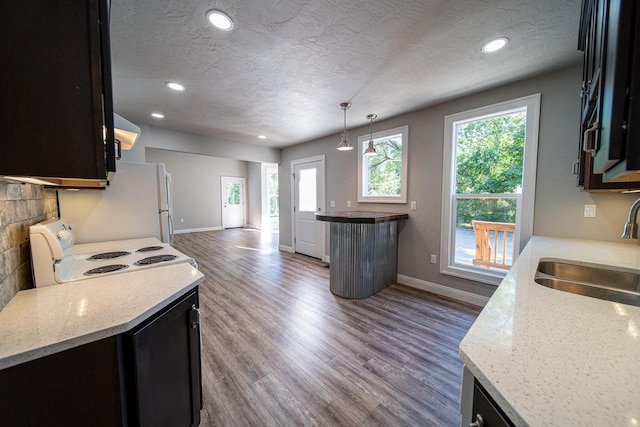 kitchen with sink, white appliances, dark wood-type flooring, hanging light fixtures, and light stone counters