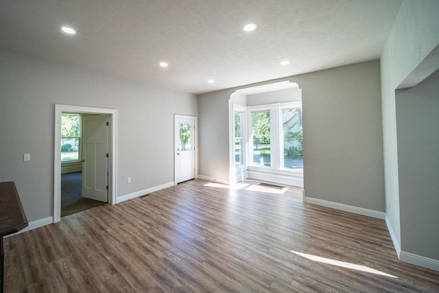 unfurnished living room with recessed lighting, baseboards, and wood finished floors