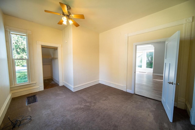 unfurnished bedroom with dark colored carpet, lofted ceiling, ceiling fan, and a closet