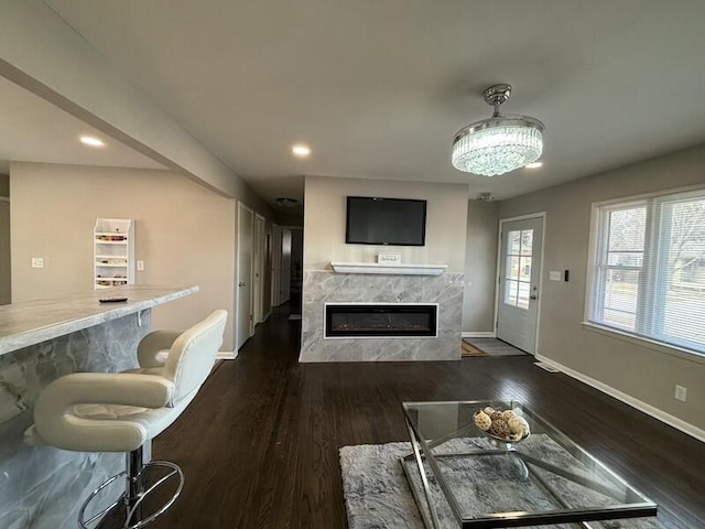 living room with a tiled fireplace, dark hardwood / wood-style flooring, and indoor bar