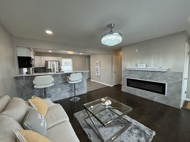 living room with dark hardwood / wood-style flooring and a tiled fireplace