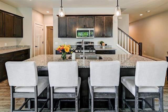 kitchen featuring stainless steel appliances, an island with sink, pendant lighting, and a kitchen bar