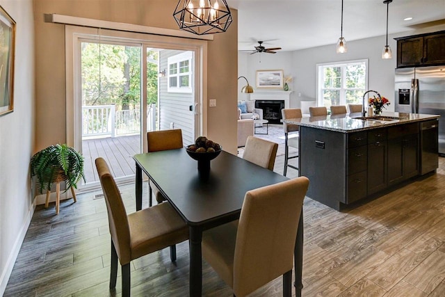 dining room with ceiling fan with notable chandelier, sink, and hardwood / wood-style floors